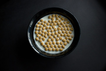 Bowl of cornflakes on dark background.
