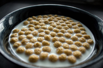 Bowl of cornflakes on dark background.