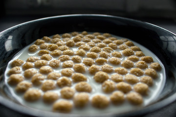 Bowl of cornflakes on dark background.