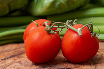 Organic Red Tomatoes on the vine arranged on natural olive wood. Solanum lycopersicum.