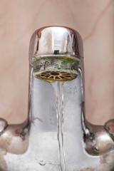 Macro of a tap with water flowing slowly during a period of scarcity