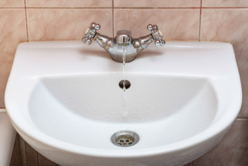 Fototapeta premium Horizontal image of a tap with water flowing slowly during a period of scarcity