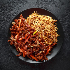 egg noodles with bean sprouts and Crispy shredded beef on black plate
