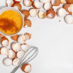 Whipping eggs with whisk. Yolks and egg protein in a cup. Corolla whisk eggs. Preparation of food and chicken eggs. Eggshell on a table. View from above.