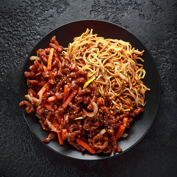 egg noodles with bean sprouts and Crispy shredded beef on black plate