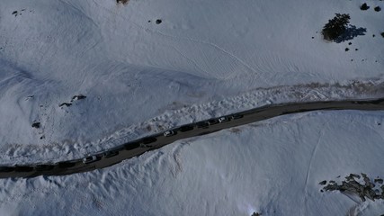Aerial drone top view photo of snowed mountain curved - snake asphalt road crossing in beautiful winter scene