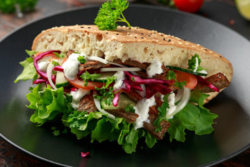 Doner kebab, fried lamb meat with vegetables and garlic sauce in turkish bread