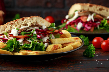 Doner kebab, fried lamb meat with vegetables, fries and garlic sauce in turkish bread