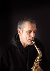 A Musician playing jazz music on his saxophone, on black background