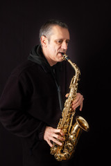 Obraz na płótnie Canvas A Musician playing jazz music on his saxophone, on black background