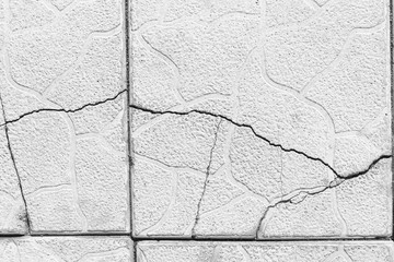 Cracked pavement tiles, gray grunge texture, cracks in the walkway 