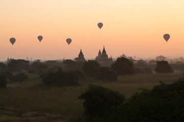 Hot air balloons floating over Bagan temples against pink sky at sunrise, Myanmar
