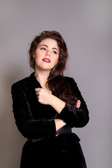 Beautiful elegant sexy brunette diva woman portrait in black clothes on grey background