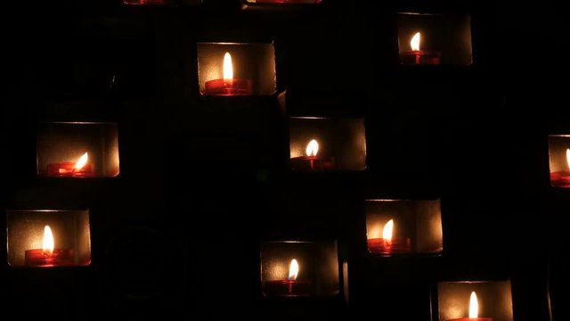 Beautiful red church candles for prayers in special niches in a catholic temple on a black background