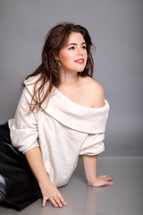 Beautiful elegant sexy brunette woman in a white sweater in the studio dreams of life
