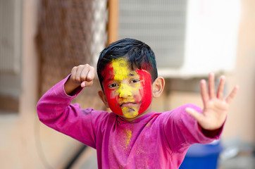 Cute Little Indian boy child with coloured face during holi indian festival looking at camera