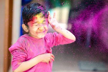 Cute Little Indian boy child with coloured paint thrown at face during holi indian festival looking at camera