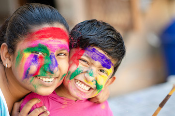 Cute adorable siblings playing with colours during holi festival of colors Indian asian caucasian creative portrait