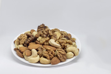 A mixture of nuts on one plate, almonds, walnuts, cashews