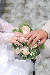 Hands and rings on wedding bouquet and groom hand