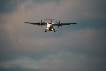front view of a medium size Airplane landing with a cloudy background