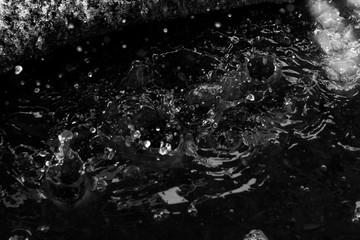 Water splash in dark with a drops of water flying, defocused bokeh 