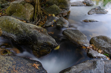 River flowing around the smooth rocks. Taken at Khlong Lan Waterfall Kamphaeng Phet Province, Thailand.