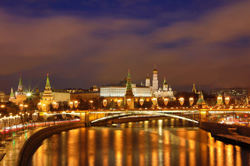 Obraz premium Illuminated Moscow Kremlin and Bolshoy Kamenny Bridge in the rays of setting sun. View from the Patriarshy pedestrian Bridge in Russia. Evening urban landscape in the blue hour