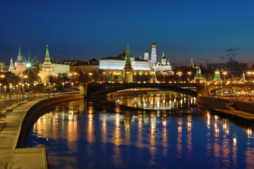 Illuminated Moscow Kremlin and Bolshoy Kamenny Bridge in the rays of rising sun. View from the Patriarshy pedestrian Bridge in Russia. Morning urban landscape in the blue hour