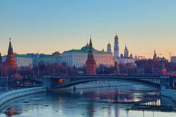 Fototapeta premium Moscow Kremlin and Bolshoy Kamenny Bridge in Russia in the rays of rising sun. View from the Patriarshy pedestrian Bridge. Morning urban landscape in the gold hour