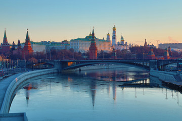 Fototapeta premium Moscow Kremlin and Bolshoy Kamenny Bridge in Russia in the rays of rising sun. View from the Patriarshy pedestrian Bridge. Morning urban landscape in the gold hour