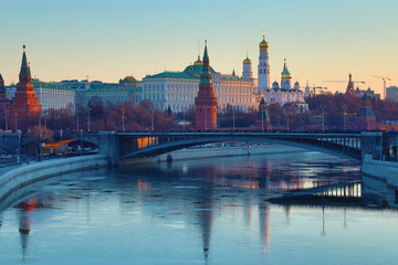 Obraz premium Moscow Kremlin and Bolshoy Kamenny Bridge in Russia in the rays of rising sun. View from the Patriarshy pedestrian Bridge. Morning urban landscape in the gold hour