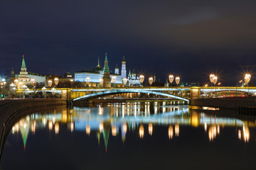 Obraz premium Illuminated Moscow Kremlin and Bolshoy Kamenny Bridge in the rays of setting sun. View from the Patriarshy pedestrian Bridge in Russia. Evening urban landscape in the blue hour
