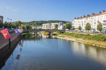 Fototapeta na wymiar The Moselle flowing through Epinal with flags on both shores