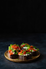 Homemade toast sandwich with rye bread, salmon, avocado, cottage cheese and microgreen sprouts on dark background. Healthy food - breakfast