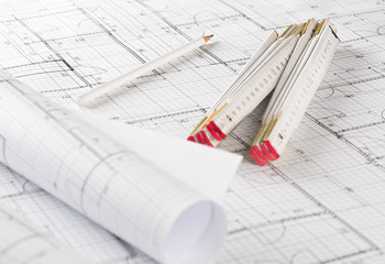 Rolls of architectural blueprint house building plans with pencil and folding ruler on blueprint background