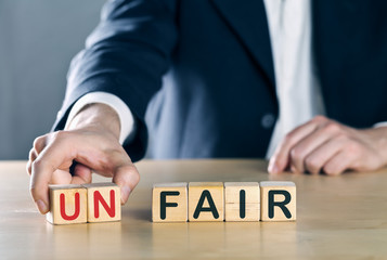 Business man puts away first two letters from the word unfair, so it becomes fair; sports or business fair play concept - obrazy, fototapety, plakaty