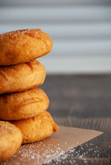 Close-up of donuts in pile on wood and white wall