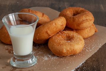 Top view of donuts and glass of milk on paper and wooden background