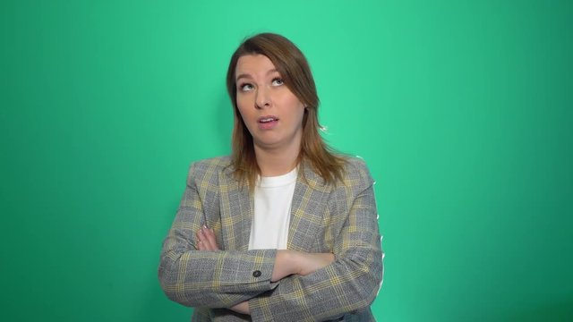 Bored woman in jacet posing with crossed arms and looking at the camera over green background cromakey