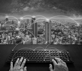 Internet networking and connection, Hand typing digital keyboard and cityscape, black and white	