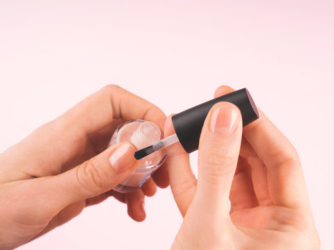 Applying nude nail polish to woman's hand