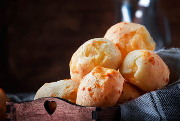 Delicious homemade golden cheese savory buns in tray, vintage wooden rustic table background, selective focus