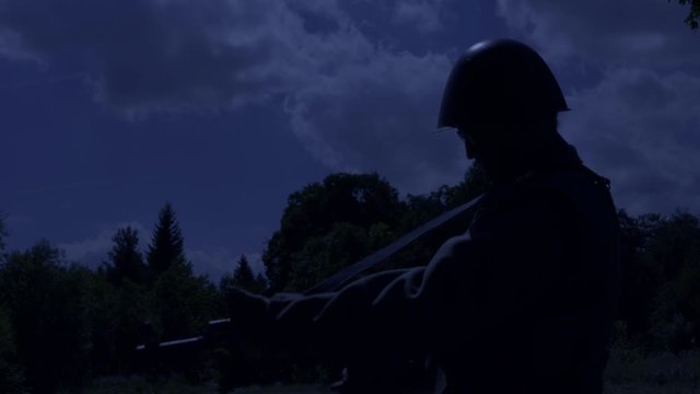 Soldier is reloading his rifle while standing on guard at night