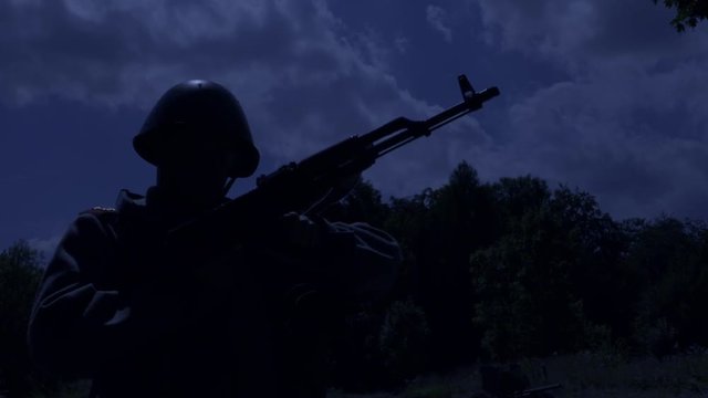 Soldier is reloading his rifle while standing on guard at night