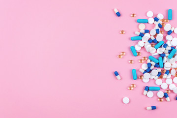 Various white and blue pills on pink background with copy space. Different medical drugs, tablets and pills. Flat lay, top view, minimal style.