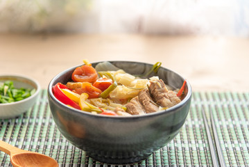 Suan cai - Traditional Chinese soup of pork and pickled Chinese cabbage in a black bowl.
