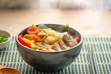 Suan cai - Traditional Chinese soup of pork and pickled Chinese cabbage in a black bowl.