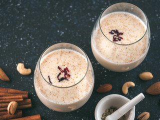 Thandai or Sardai cold drink made during Holi festival. Cold milk drink in glass, with ingredients - nuts and spices. Copy space