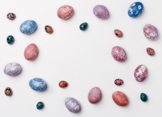 Creative Frame background with quail, pink, purple and blue easter eggs with copy space for text. isolated on white background. Flat lay, top view.